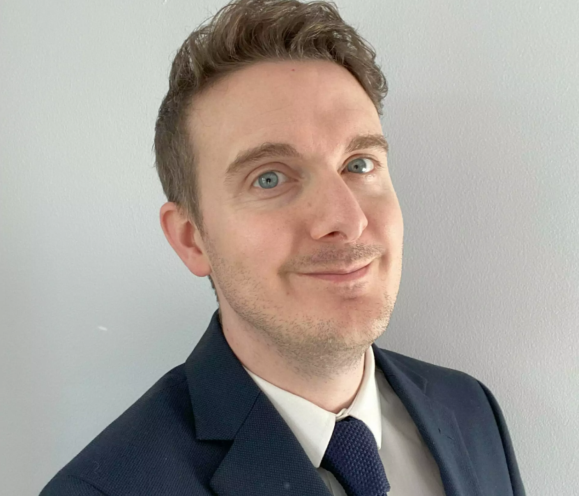 Headshot of Dr James Pearson smiling wearing a suit and tie